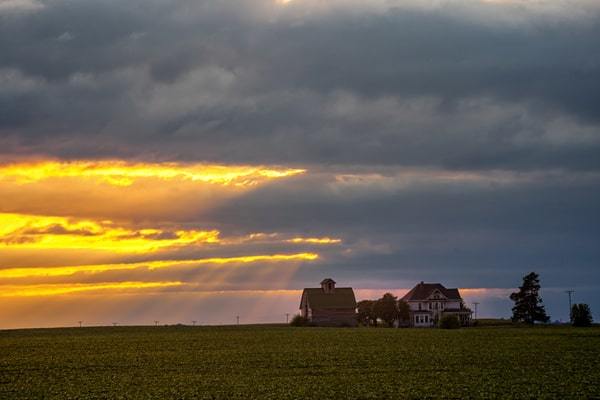 Sun peeking through clouds over Central Illinois farmhouse